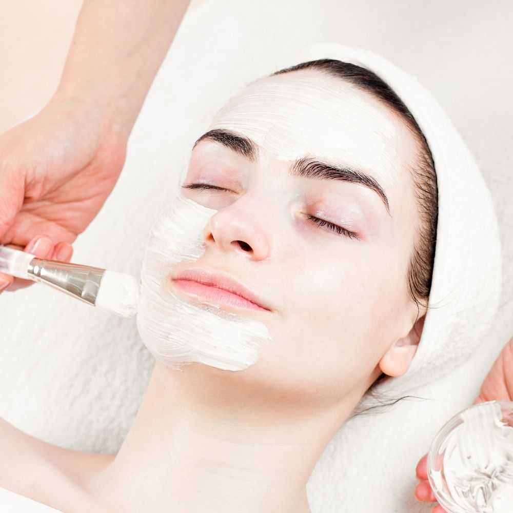 Woman receiving a facial treatment with a mask being applied.