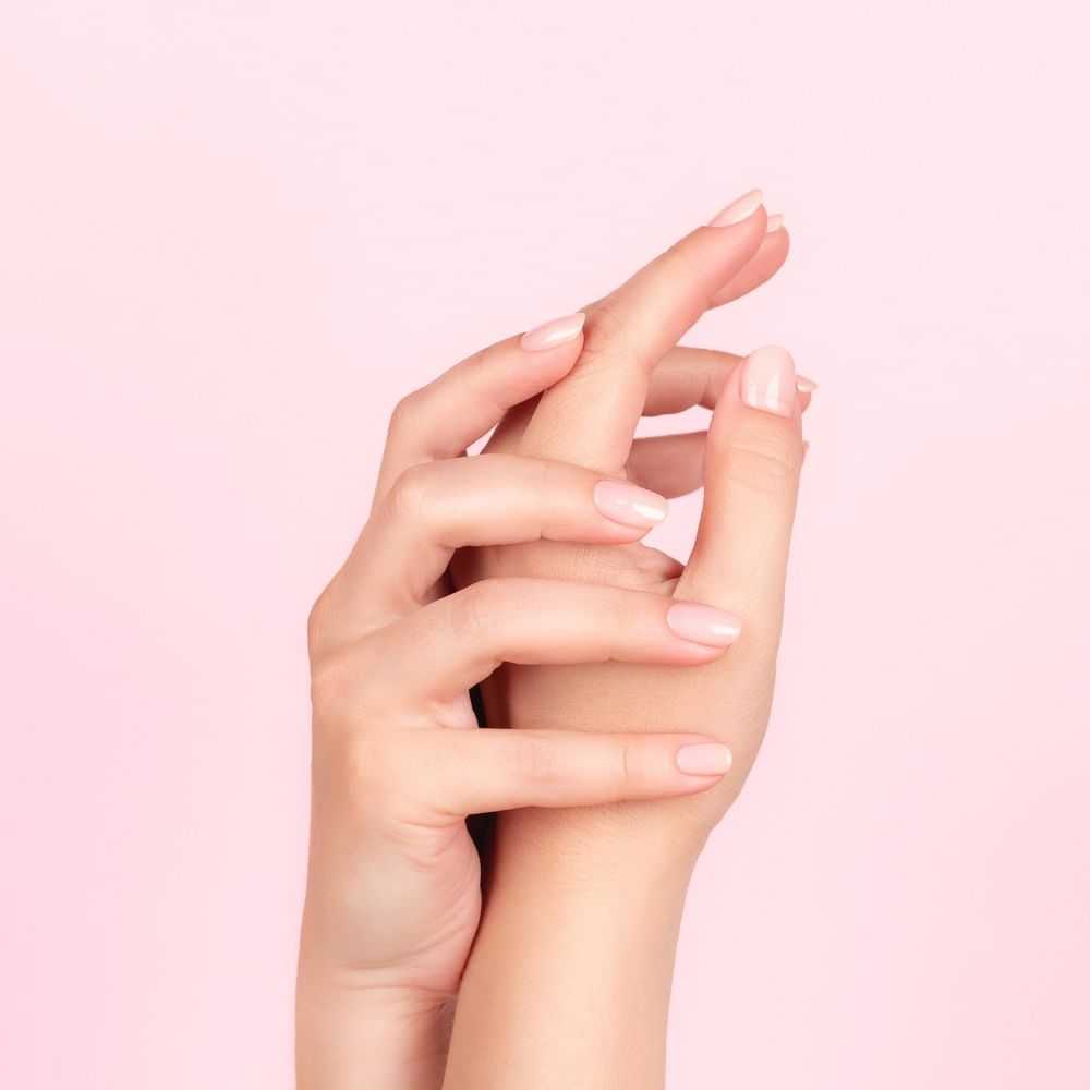 Two hands with manicured nails intertwined against a pink background.