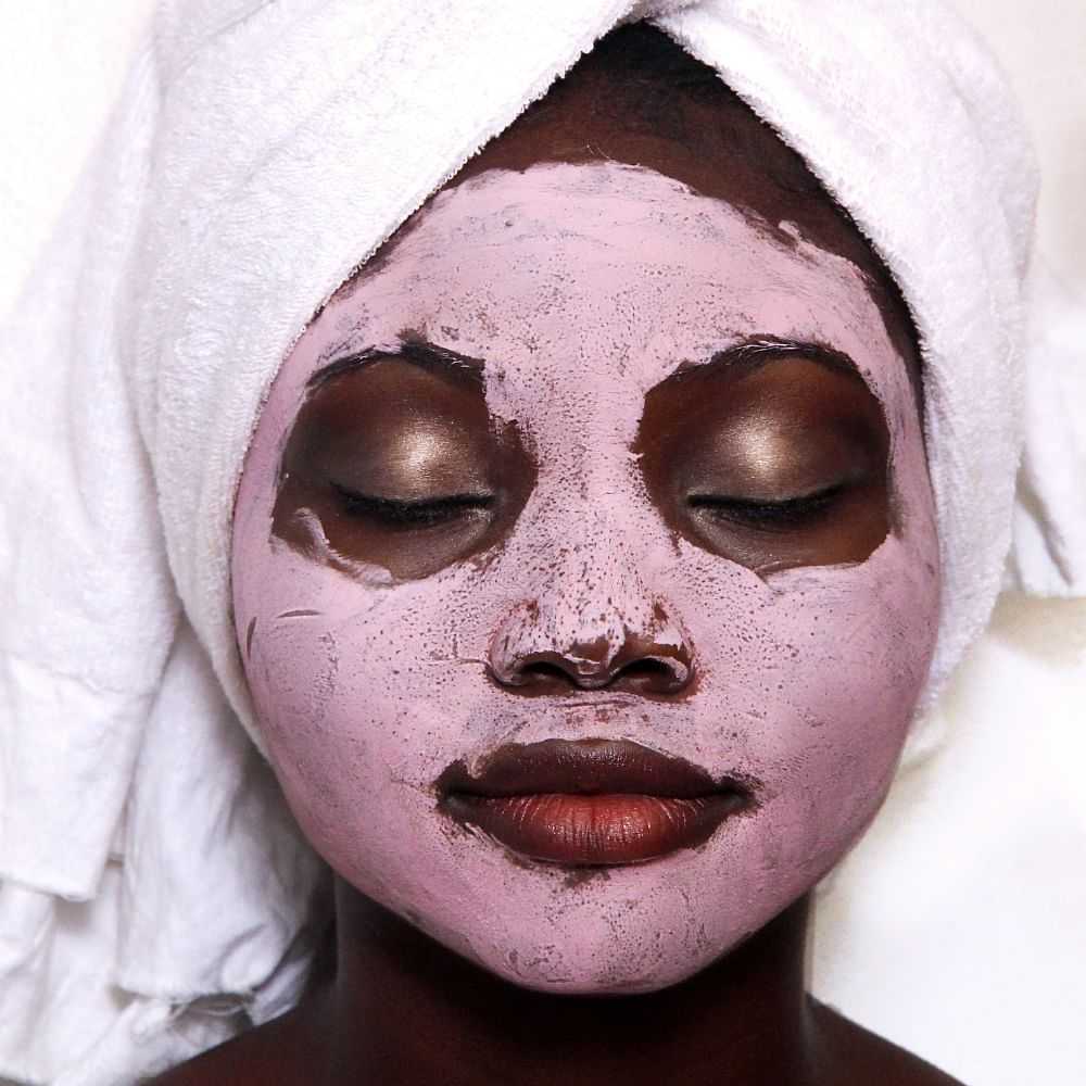 Woman with a facial mask and towel on her head relaxing.