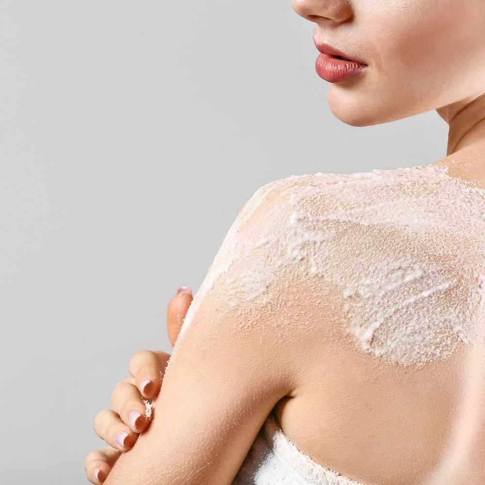 Woman applying moisturizer on her shoulder.