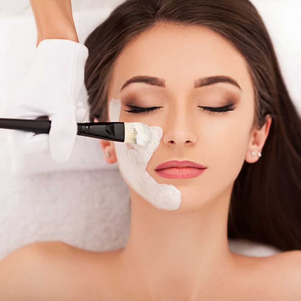 Aesthetician applying facial mask to a woman at a spa.