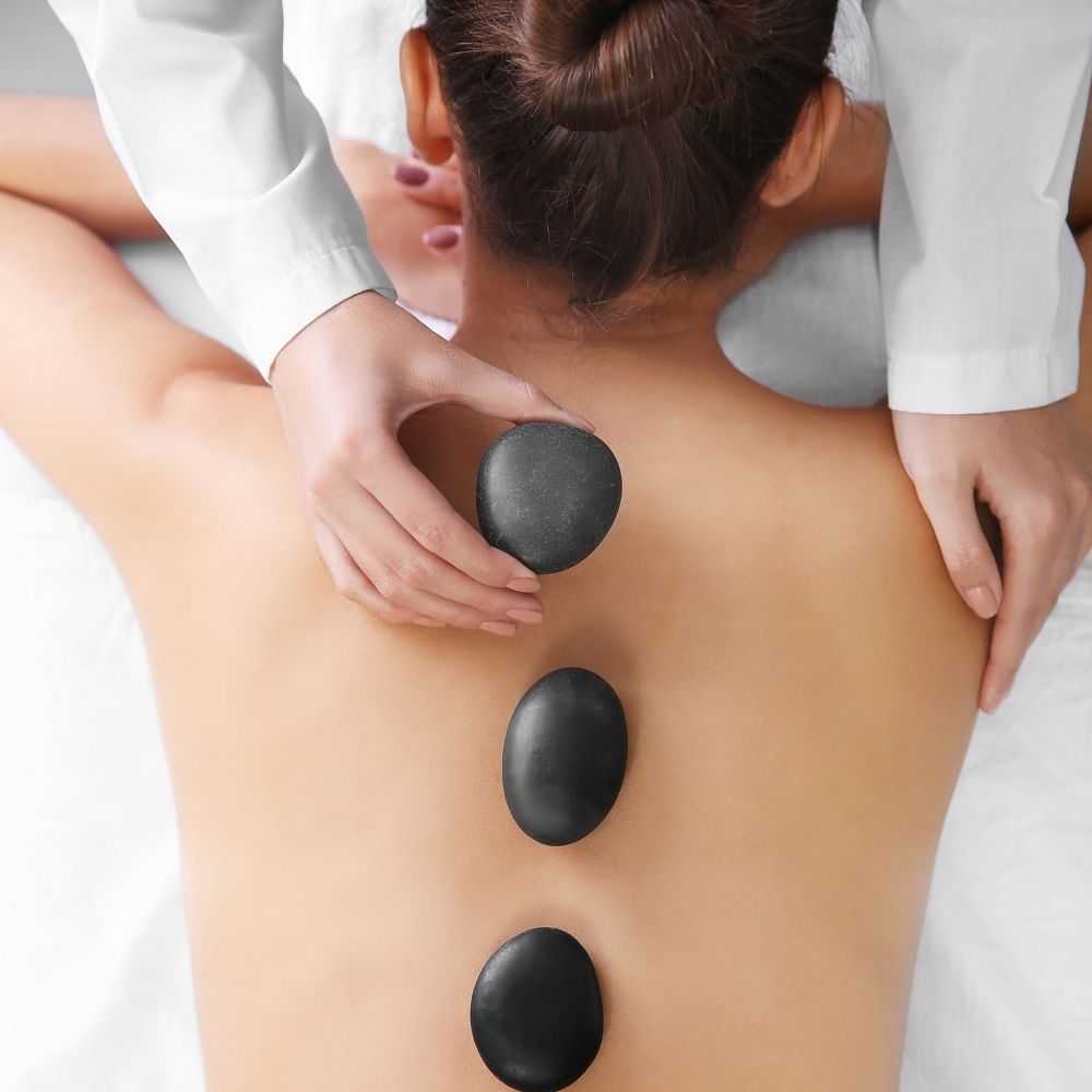 Woman receiving hot stone therapy on her back at a spa.