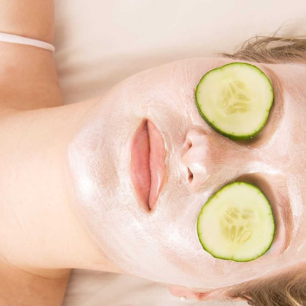 Person with a facial mask and cucumber slices on eyes.