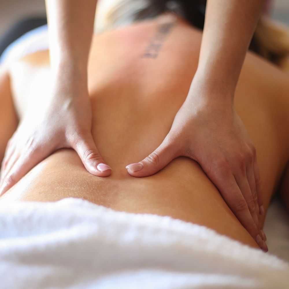 Hands giving a back massage to a person lying down.