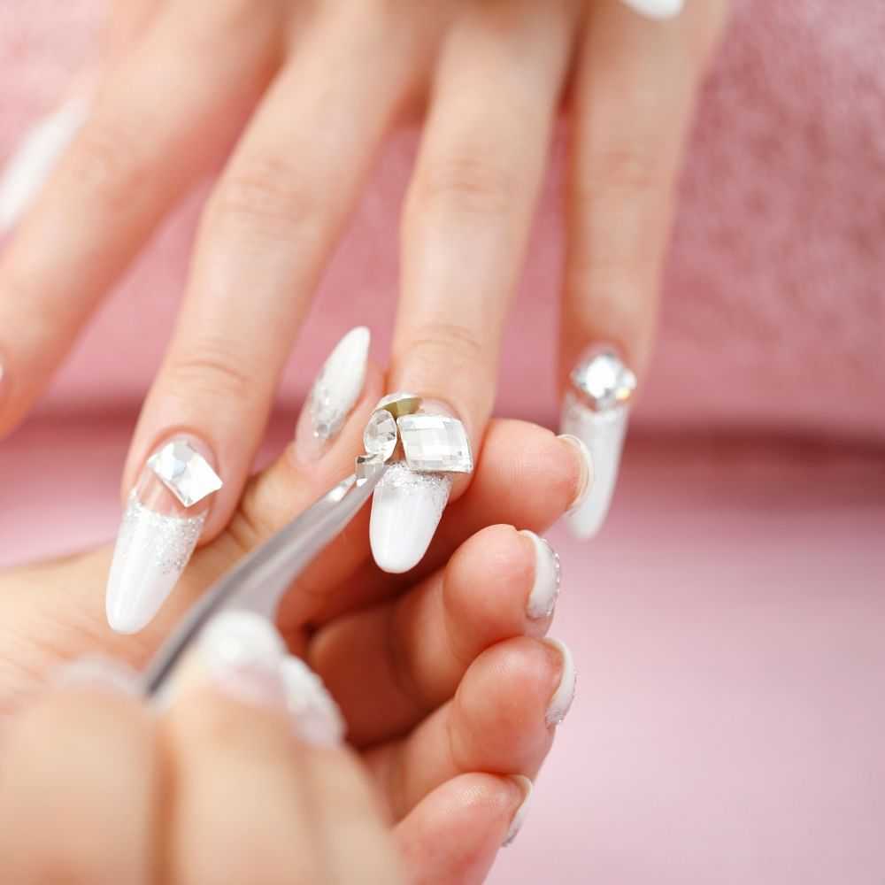 Applying rhinestone to freshly manicured, long nails.